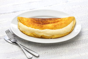  An delicious omelet souffle, served on a white plate with silverware. 