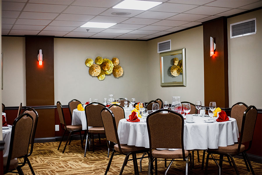 A large fine-dining banquet hall in Springfield, IL with white table clothes and brown wallpaper that can be rented for meetings and banquets of all sizes.