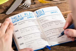 A person in Springfield, IL planning out their meal plans for the week by writing it in a blue journal.
